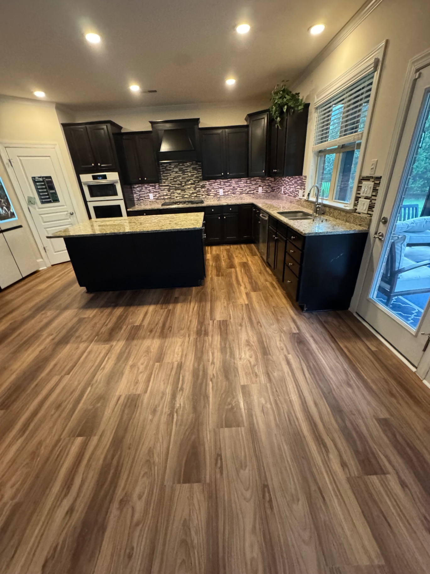Warm walnut LVP flooring in open kitchen with dark cabinets