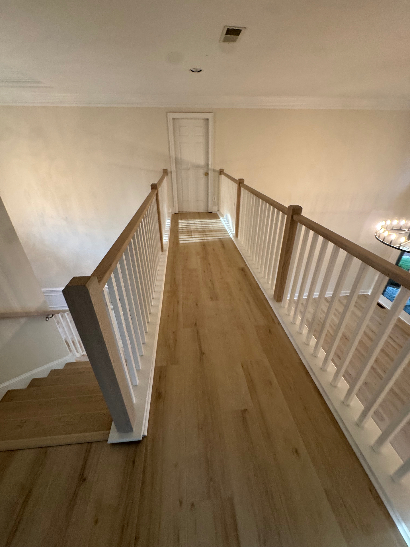Wide-plank hardwood flooring on upstairs landing with railings