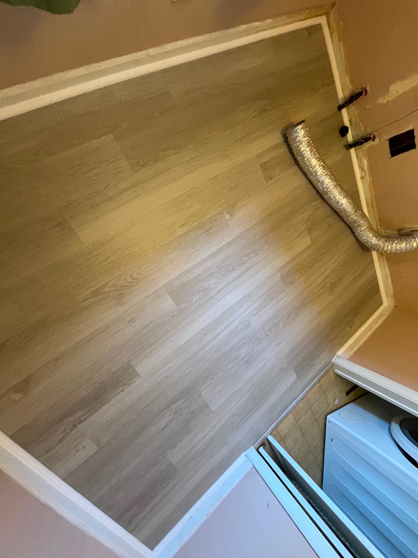 Light grey vinyl plank flooring installation in laundry area