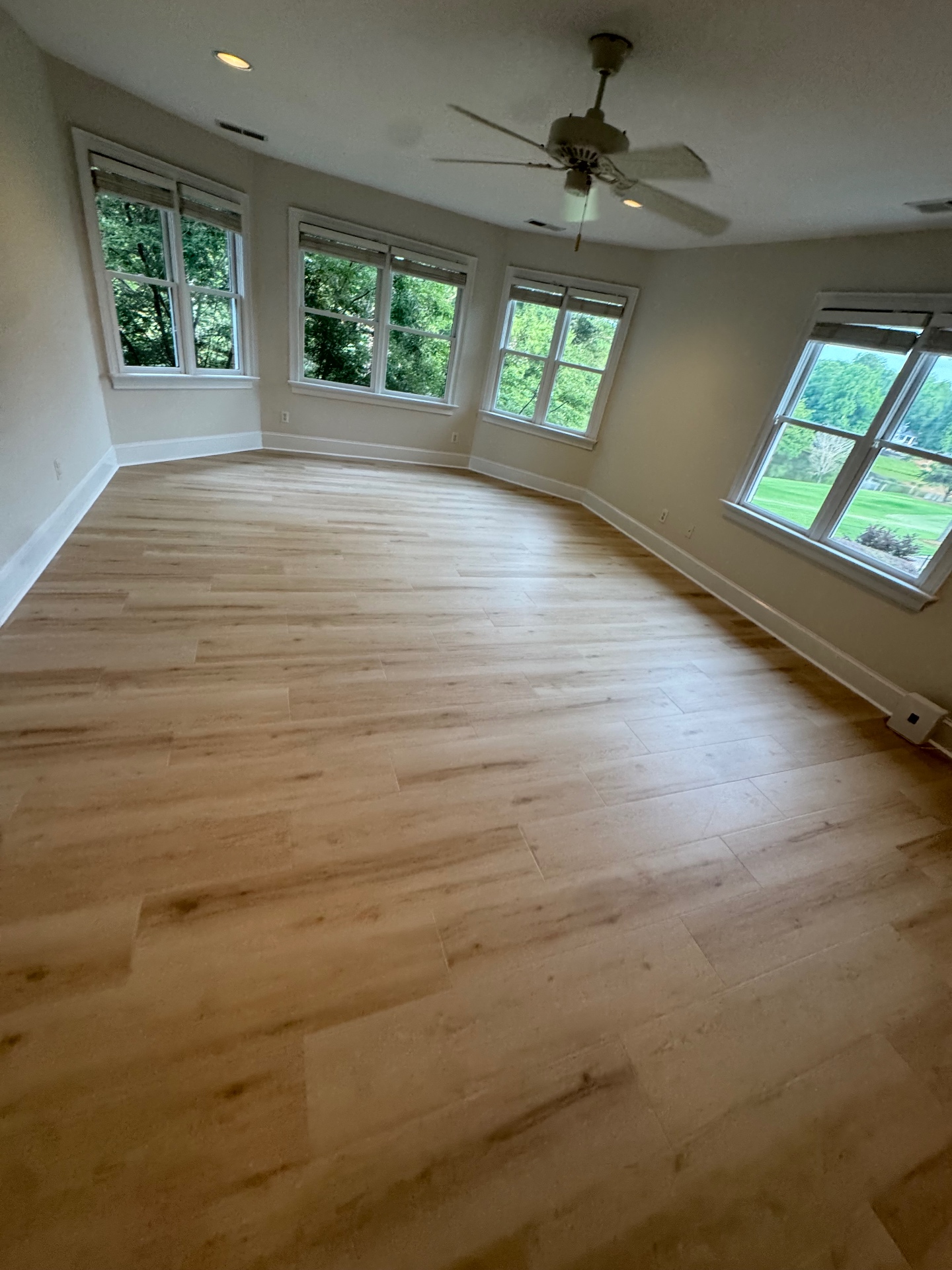 Light oak luxury vinyl plank flooring in sunlit bay-window living room
