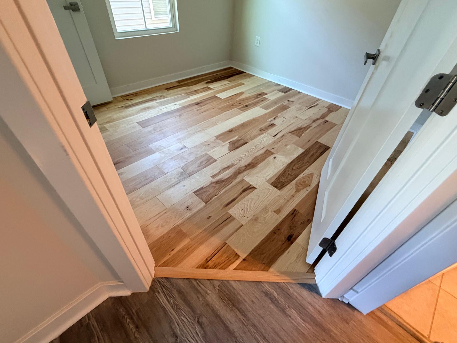 Natural hickory hardwood transition to LVP hallway
